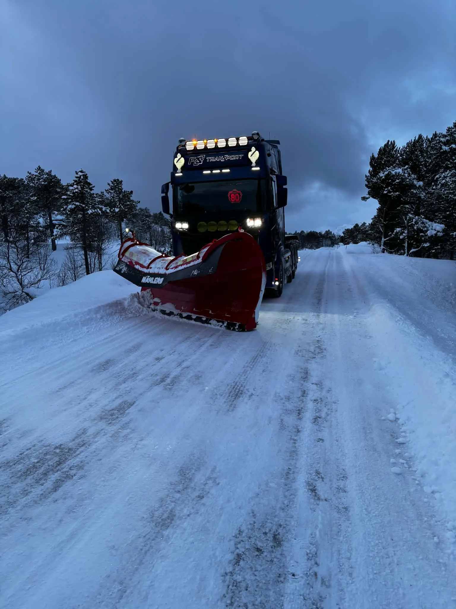 Traktor med strøer på snødekt vei