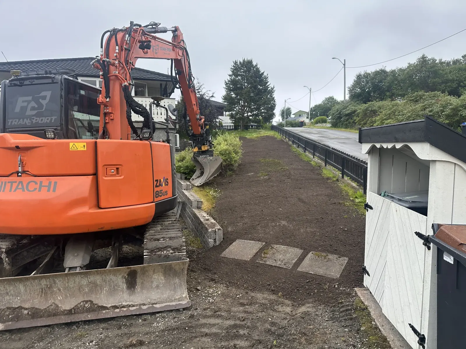 Gravemaskin under grunnarbeid ved en bolig