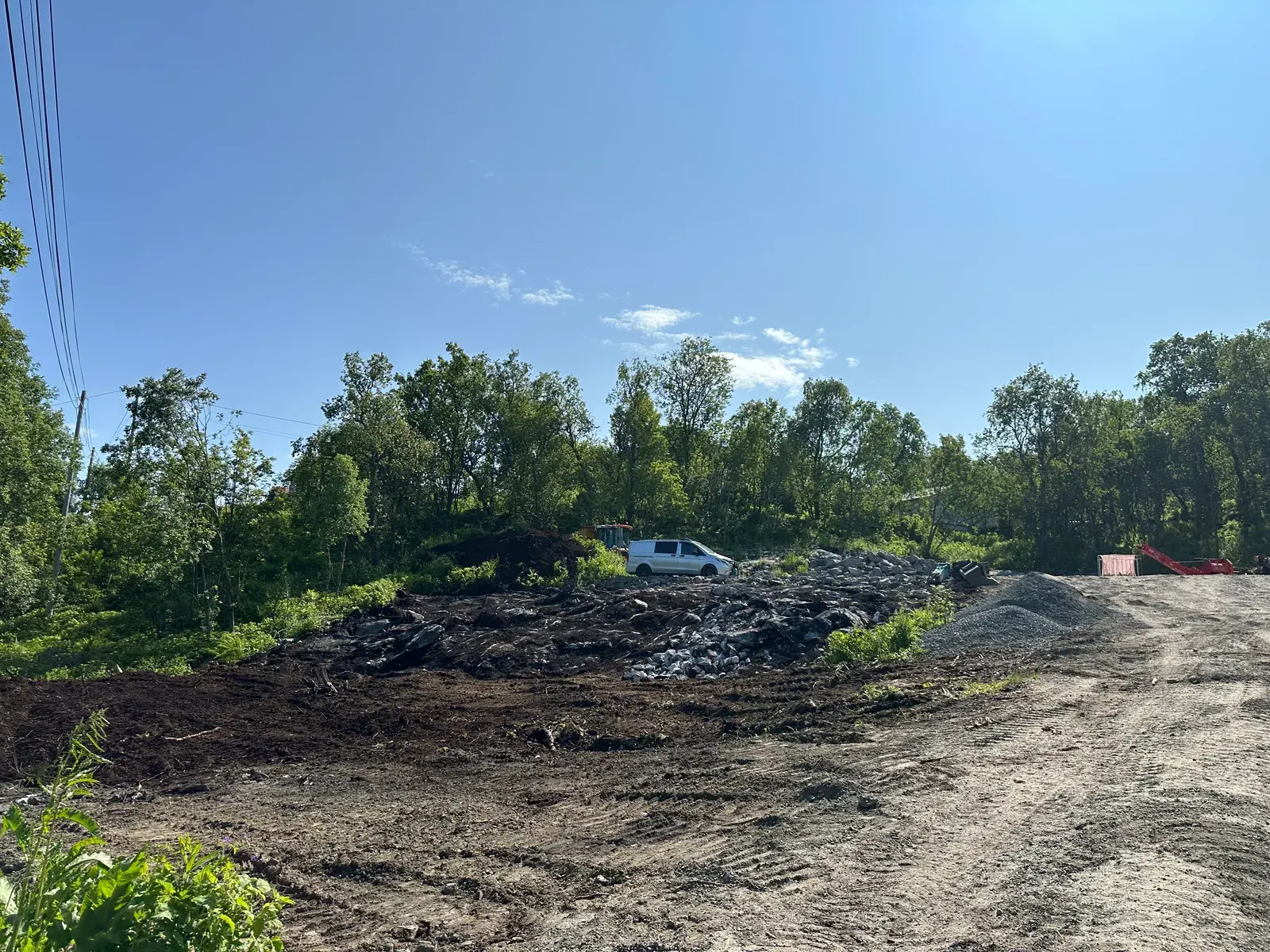 Ryddet hustomt med jord og grus foran skog