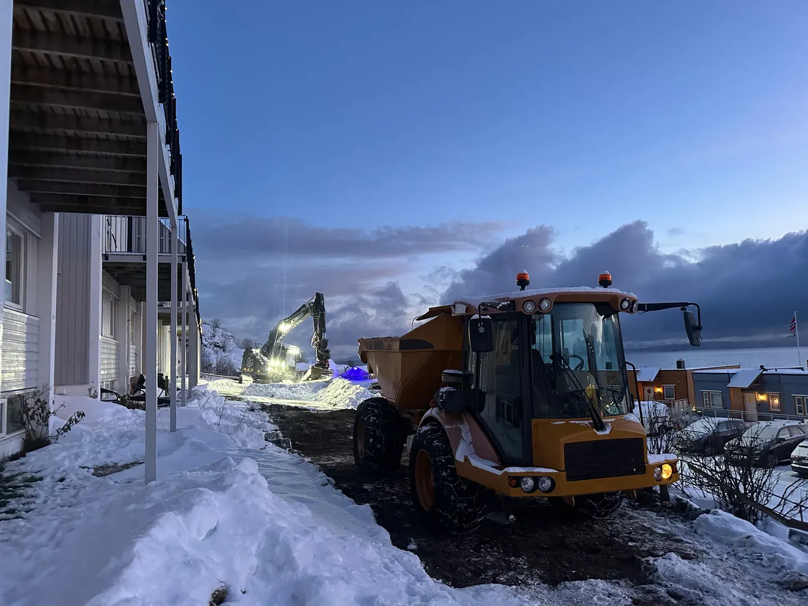 Gul dumper ved boligblokk i snø