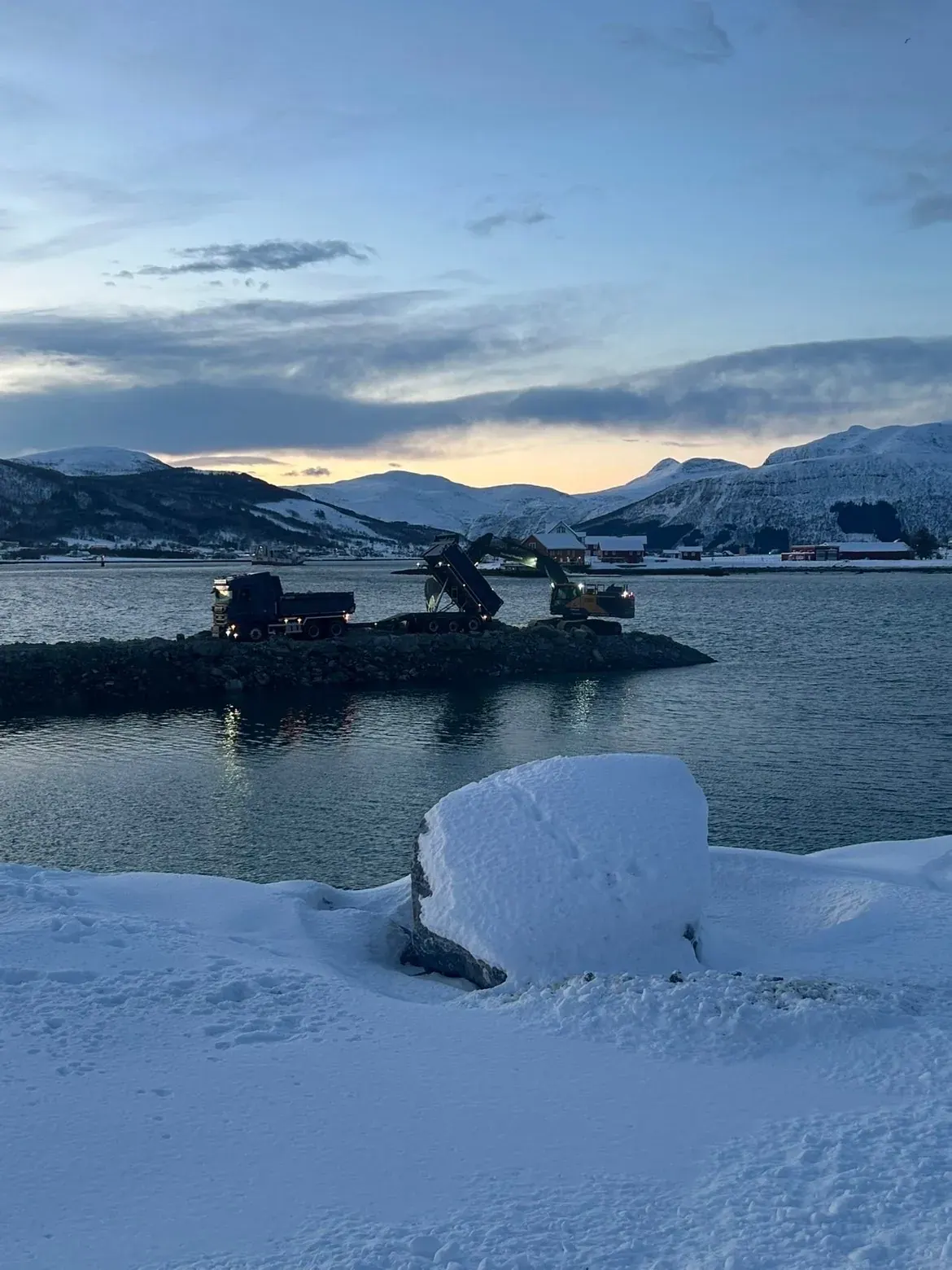 Tipping av stein ut i sjøen fra en snødekt fylling