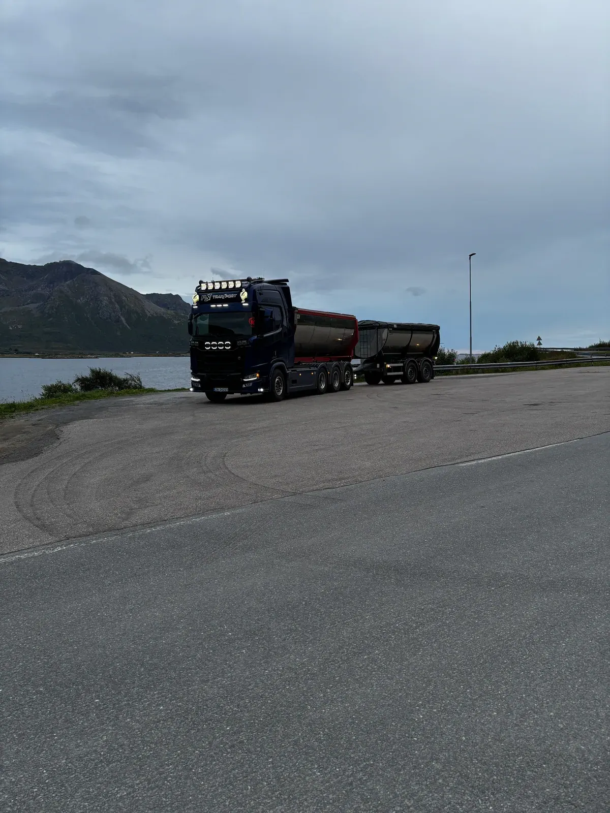 Blå lastebil med henger ved sjøen