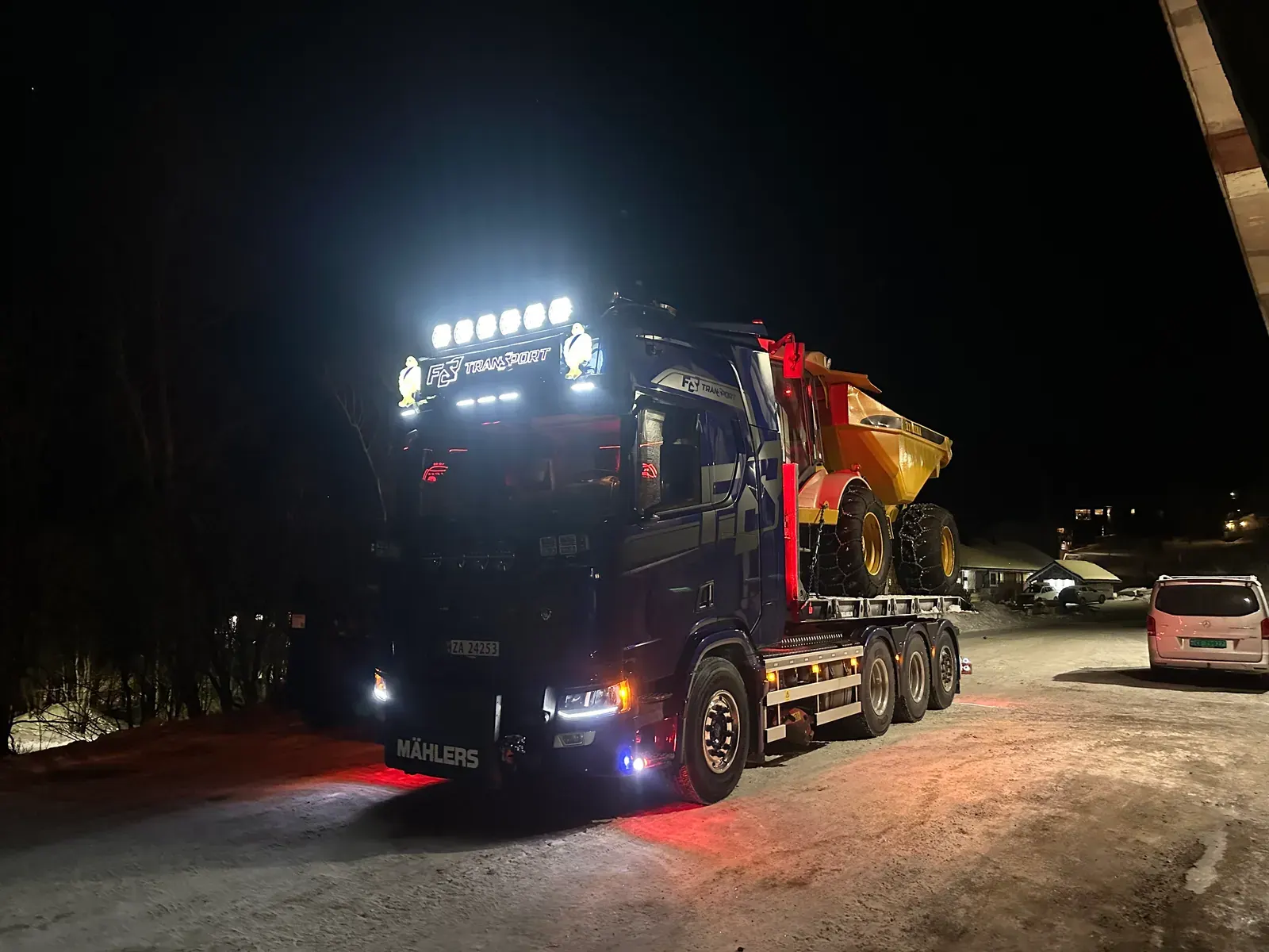 Krokbil med gul dumper på lasteplanet om kvelden
