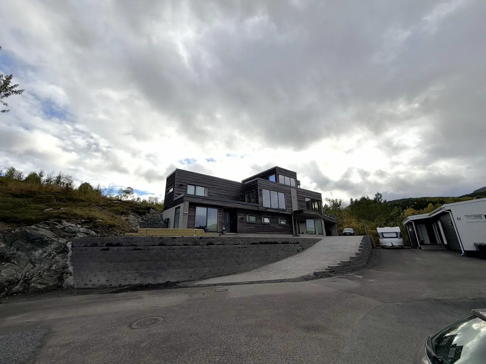 Lang støttemur og innkjørsel foran en ny bolig