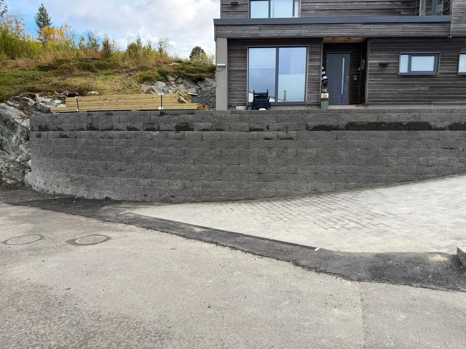 Høy støttemur av blokker foran en bolig