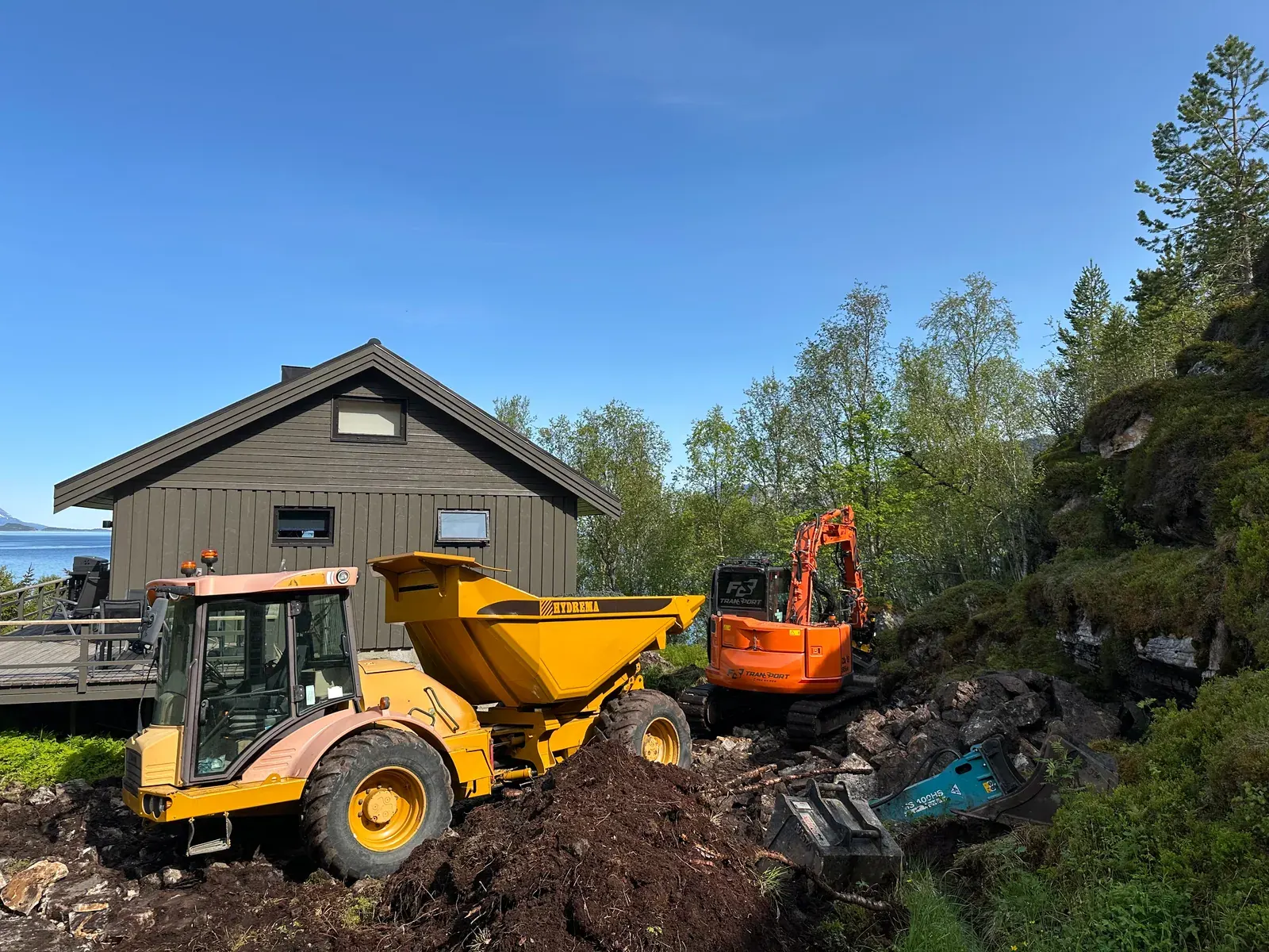 Dumper og gravemaskin ved en bolig under arbeid med septik