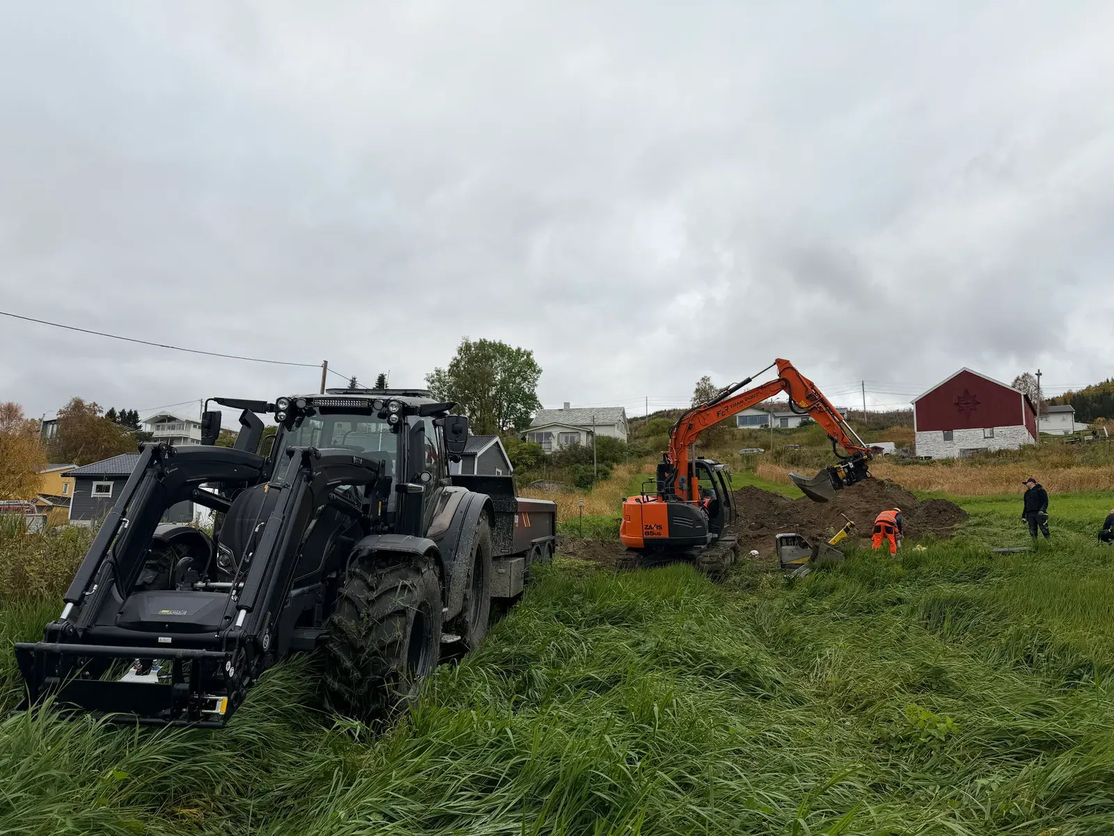 Traktor og gravemaskin på et jorde ved en vannledning